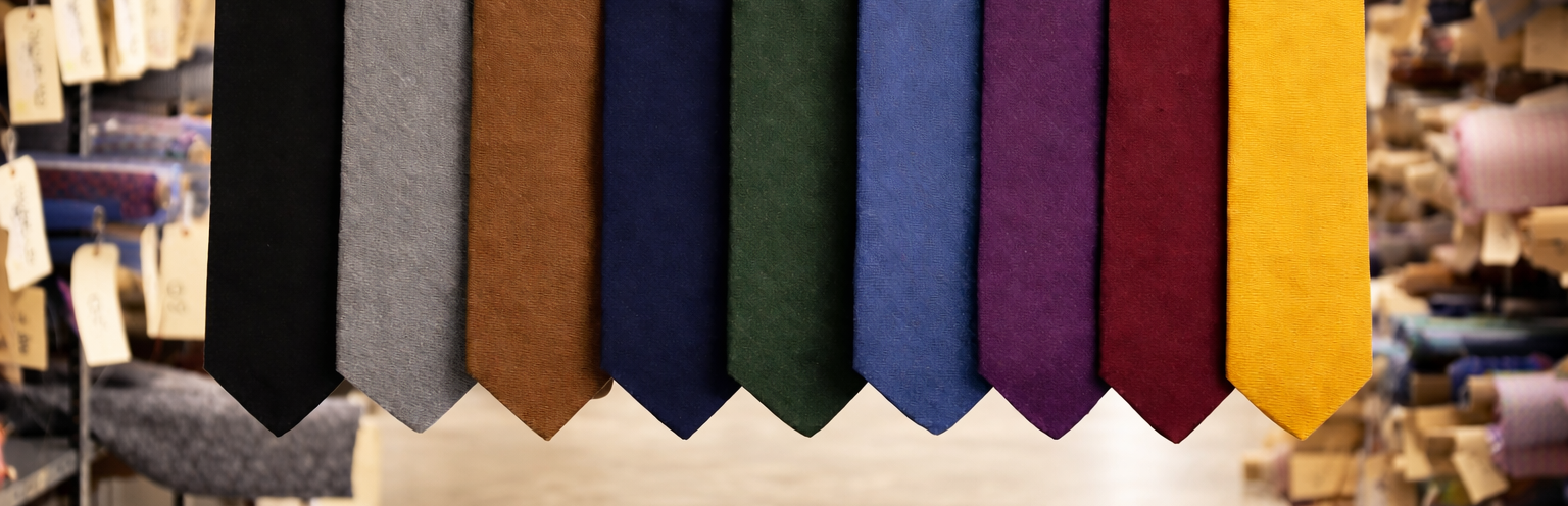 Row of colorful ties hanging on a rack in a store setting.